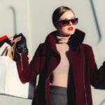 Mujer vestida a la moda con lentes oscuros, sostiene bolsas de compra con ropa para mujer en España