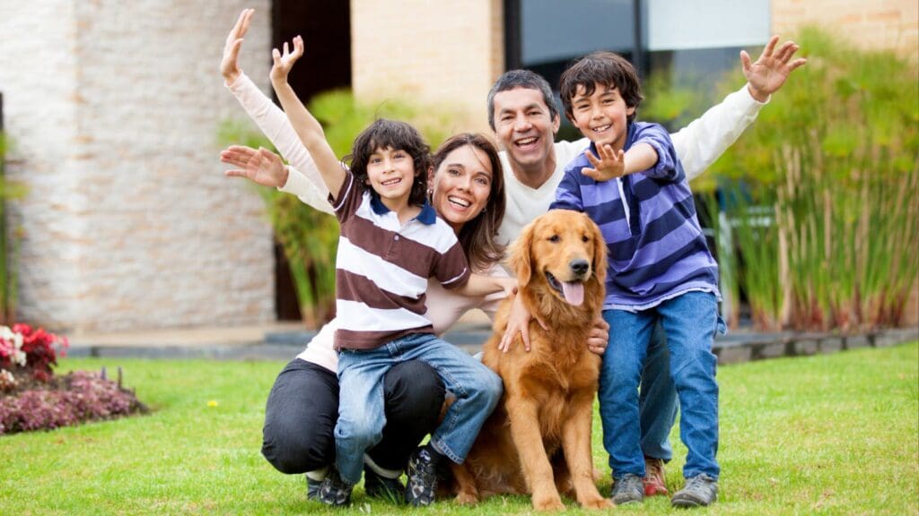 Familia con niños y mascotas explorando su nueva casa con jardín y espacios amplios.