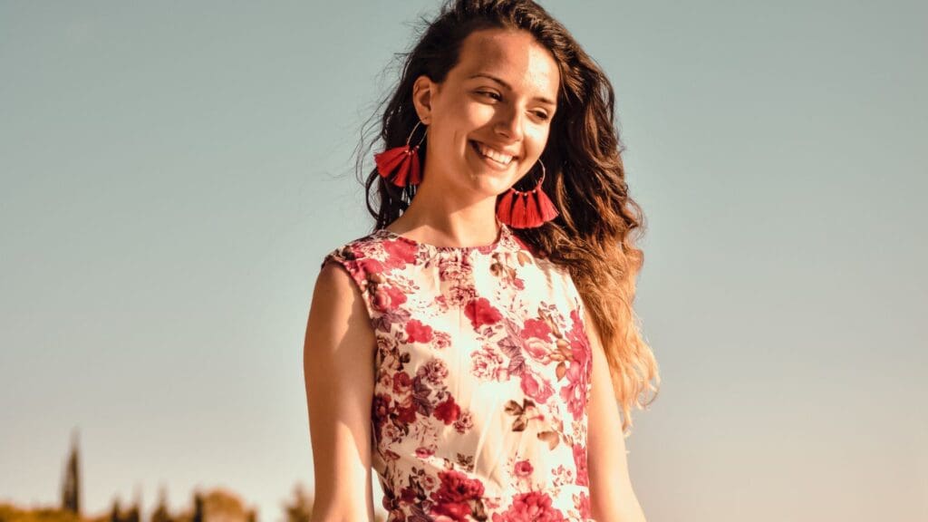 Mujer disfrutando en la playa con vestido de playa artesanal y accesorios, mostrando un estilo único y bohemio.