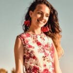 Mujer disfrutando en la playa con vestido de playa artesanal y accesorios, mostrando un estilo único y bohemio.