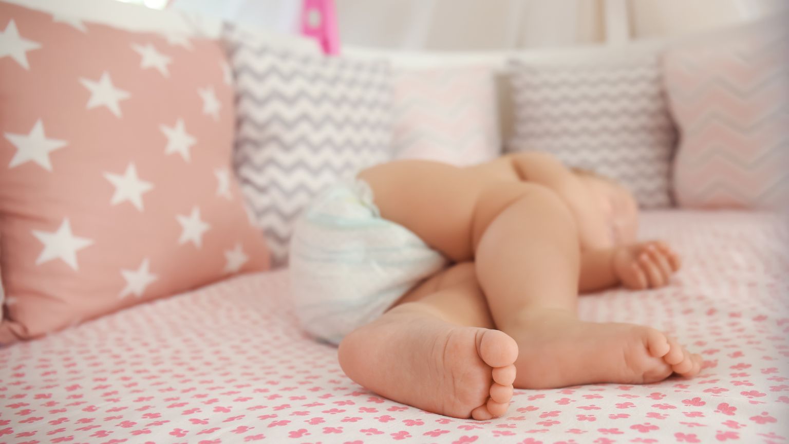 Bebé durmiendo plácidamente en una cuna, rodeado de peluches y productos de calidad para el sueño infantil.