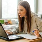 Estudiantes participando en clases de idiomas online desde casa, con ordenadores portátiles, en un entorno cómodo y flexible