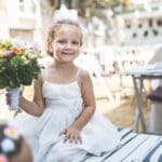 Niña de arras con peinado elegante y vestido de boda para ceremonia