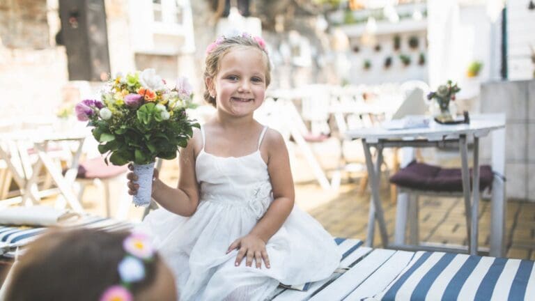 Niña de arras con peinado elegante y vestido de boda para ceremonia