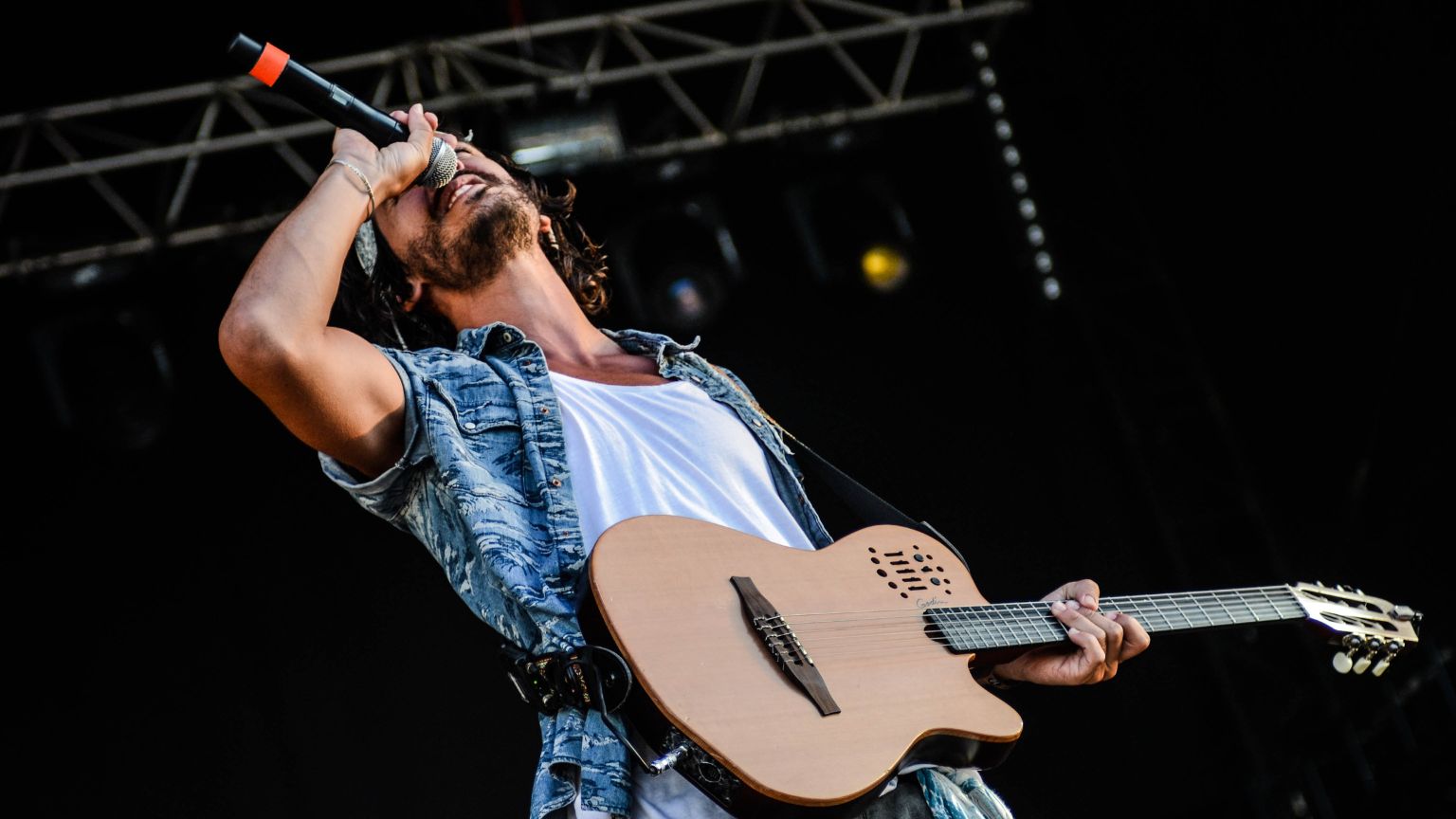 Escenario íntimo de festival de música donde un artista interpreta canciones con guitarra, creando una conexión cercana con el público en un ambiente acogedor.