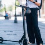 Persona conduciendo un patinete eléctrico en una ciudad, representando una opción de movilidad sostenible y eficiente para trayectos urbanos.