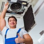 Técnico instalando un sistema de aire acondicionado en un local comercial, representando servicios profesionales de climatización para empresas.