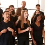 Estudiante recibiendo clases de canto en un estudio de música profesional, aprendiendo técnicas vocales con un micrófono, bajo la guía de un profesor experto.