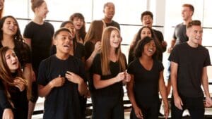 Estudiante recibiendo clases de canto en un estudio de música profesional, aprendiendo técnicas vocales con un micrófono, bajo la guía de un profesor experto.