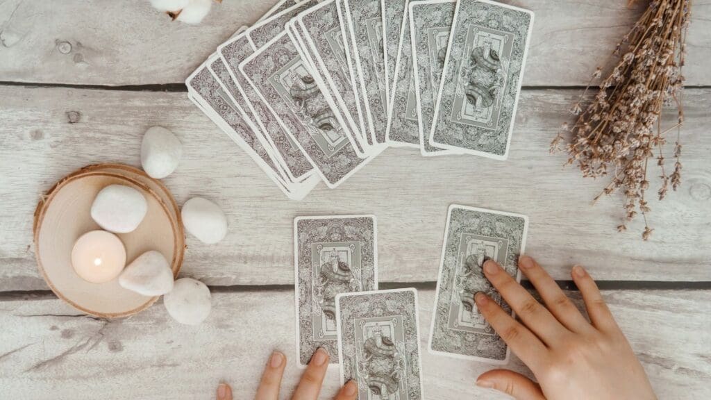 Mesa decorada con cartas del tarot y un libro abierto. Ambiente esotérico con velas y un fondo cálido, ideal para representar una lectura espiritual.