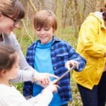 Niños participando en una actividad educativa al aire libre que fomenta el aprendizaje activo, la creatividad y la exploración del entorno natural.