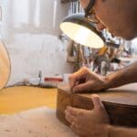 Lutier trabajando en la fabricación artesanal de una guitarra española en taller, resaltando tradición y calidad en cada detalle.