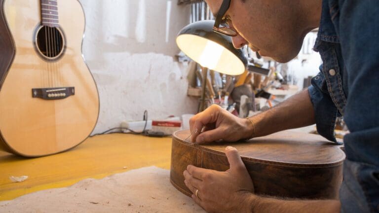 Lutier trabajando en la fabricación artesanal de una guitarra española en taller, resaltando tradición y calidad en cada detalle.