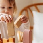 Niños jugando con bloques de madera educativos en un ambiente luminoso. Juegos sostenibles que fomentan la creatividad y el desarrollo infantil.