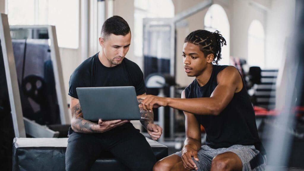 Persona realizando ejercicio personalizado en un gimnasio, con un entrenador ofreciendo guía profesional. Representación de un plan de entrenamiento adaptado y enfocado en resultados saludables.