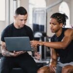 Persona realizando ejercicio personalizado en un gimnasio, con un entrenador ofreciendo guía profesional. Representación de un plan de entrenamiento adaptado y enfocado en resultados saludables.