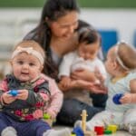 Niños pequeños jugando y aprendiendo en un entorno seguro y educativo con actividades adaptadas a su desarrollo.