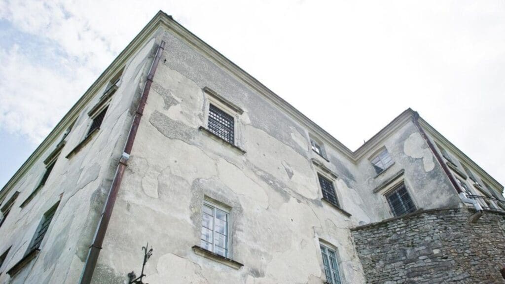 Edificio con daños visibles por humedad en las paredes, manchas oscuras y pintura desconchada, representando los efectos de un ambiente húmedo.