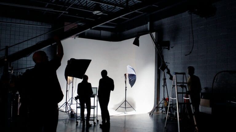 Equipo de producción cinematográfica trabajando en un set de rodaje con cámaras, luces y técnicos audiovisuales.