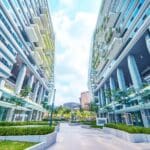 Edificio empresarial sostenible con diseño moderno, paneles solares en el techo y rodeado de naturaleza, representando la integración de sostenibilidad y funcionalidad.