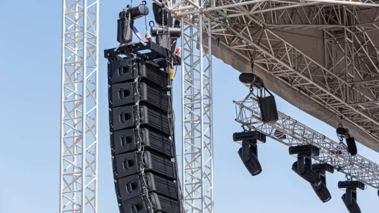 Vista de un escenario iluminado con equipos de sonido profesional, pantallas LED y efectos visuales en un evento en vivo.