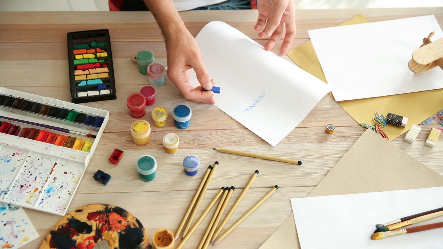 Artista dibujando un cómic en una mesa de trabajo con bocetos, lápices y herramientas de dibujo, representando el proceso creativo y técnico del arte del cómic.