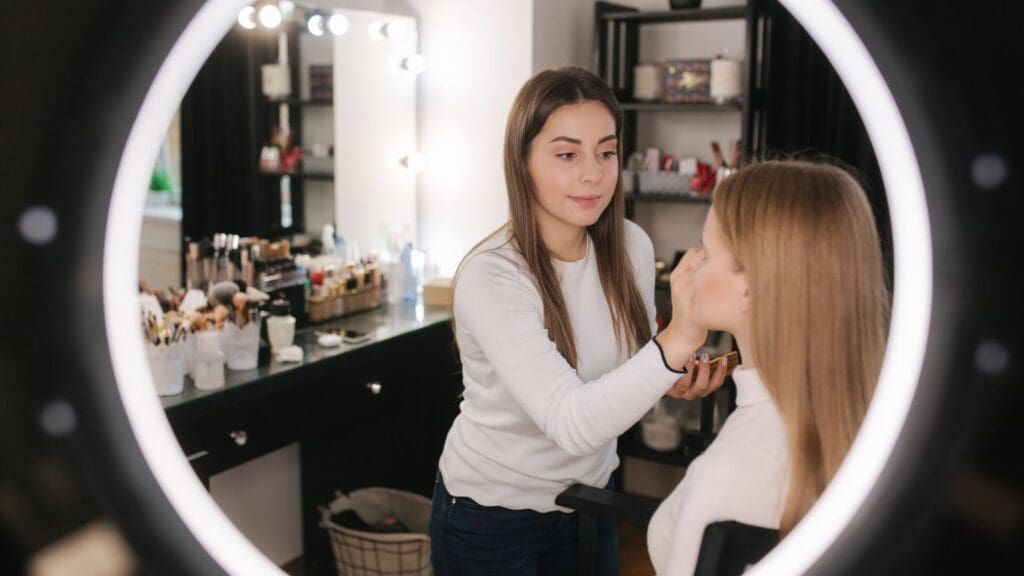 Mujer practicando técnicas de automaquillaje en un curso con productos de maquillaje y herramientas profesionales