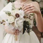 Novia con vestido de alta costura, bordado con detalles elegantes y encaje, posando en un entorno sofisticado. Perfecto para destacar exclusividad y glamour en bodas.