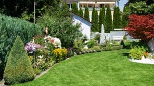 Jardín sostenible con césped verde, arbustos podados y flores coloridas que promueven la biodiversidad en un entorno urbano.