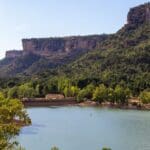 Paisaje de la Serranía de Cuenca con un lago rodeado de montañas y vegetación, ideal para disfrutar del turismo rural y la naturaleza.