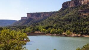 Paisaje de la Serranía de Cuenca con un lago rodeado de montañas y vegetación, ideal para disfrutar del turismo rural y la naturaleza.