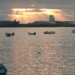 Atardecer en la Bahía de Cádiz visto desde un barco. Cielo teñido de colores cálidos reflejados en el agua, ideal para un paseo exclusivo.