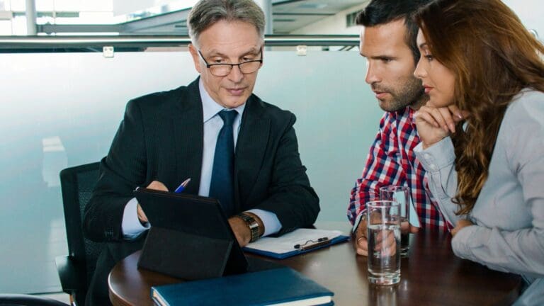 Asesor financiero explicando opciones hipotecarias a clientes en una oficina, destacando servicios financieros para inmobiliarias y maximización de rentabilidad.