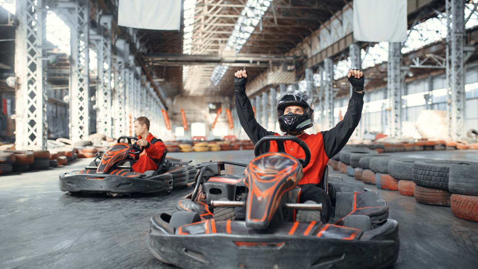 Pilotos compitiendo en una carrera de karting, tomando curvas a alta velocidad en un circuito profesional.