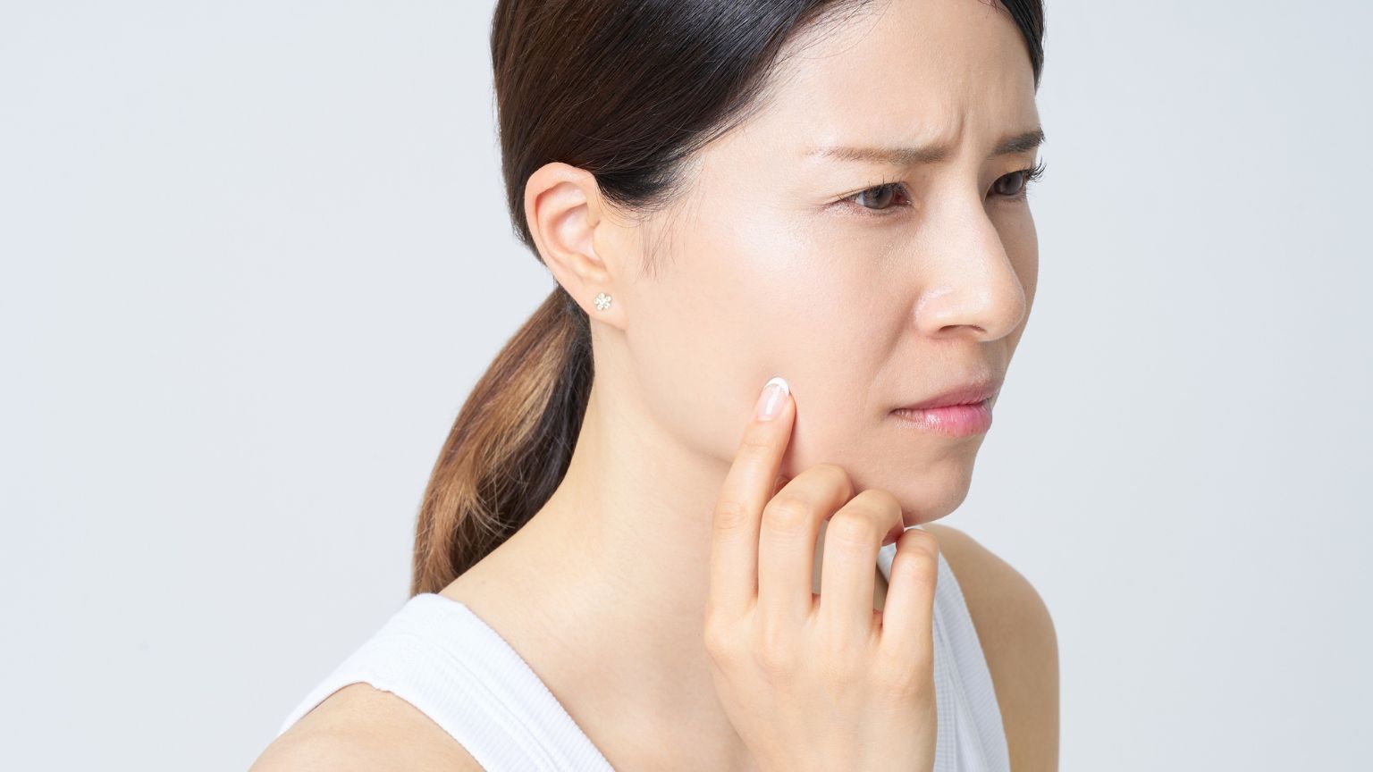 Mujer observando su piel con preocupación después de un tratamiento estético, reflejando la importancia de evitar errores comunes en procedimientos de belleza.