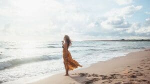 A free-spirited woman wearing a flowy bohemian dress, walking confidently through a natural setting. The earthy tones, delicate embroidery, and relaxed silhouette highlight the effortless elegance and individuality of bohemian fashion.