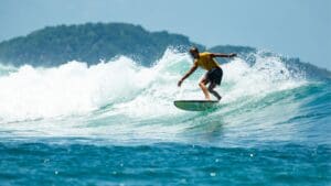 Surfer riding a wave at sunset, embracing the ocean’s natural beauty and the mental health benefits of surfing.