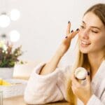 Mujer emprendedora vendiendo cosméticos desde casa, usando redes sociales para promocionar su negocio de belleza.