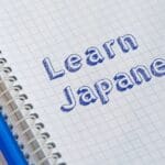 Estudiante practicando escritura en japonés con cuaderno y lápiz, aprendiendo kanji y vocabulario japonés en un ambiente de estudio.