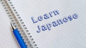 Estudiante practicando escritura en japonés con cuaderno y lápiz, aprendiendo kanji y vocabulario japonés en un ambiente de estudio.