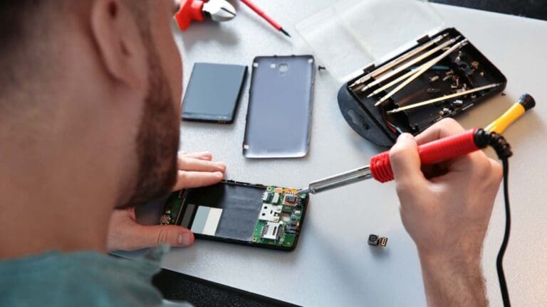 Técnico reparando un móvil con herramientas en un taller especializado. Dispositivos reacondicionados con garantía y calidad asegurada.