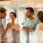 Grupo de personas disfrutando de una cata de vinos en una bodega cerca de Barcelona, rodeados de viñedos y barricas de vino.