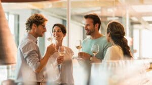 Grupo de personas disfrutando de una cata de vinos en una bodega cerca de Barcelona, rodeados de viñedos y barricas de vino.