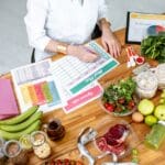 Nutricionista diseñando una dieta personalizada con alimentos saludables y una lista de planificación.