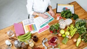 Nutricionista diseñando una dieta personalizada con alimentos saludables y una lista de planificación.