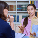 Adolescente sentada en consulta psicológica hablando con una terapeuta especializada en salud mental juvenil.