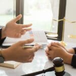 Cliente recibiendo asesoría legal en una oficina, contrastando con un proceso de defensa legal en un entorno judicial.