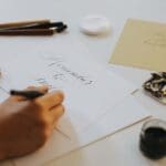 Calígrafo profesional escribiendo a mano con tinta negra sobre papel, representando la elegancia del diseño caligráfico tradicional