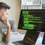 Técnico informático realizando tareas de mantenimiento en una empresa con equipos conectados y soporte remoto activo.