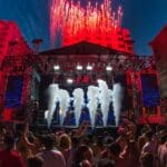 Escenario iluminado en un evento cultural urbano con público disfrutando en un espacio abierto
